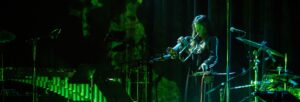 A woman playing the trumpet on stage, lit by green light