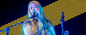 A woman with fair hair singing into a microphone