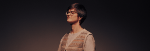 A woman with short hair and glasses has her eyes closed.
