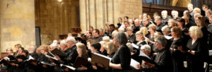 A large choir is in a church. All the performers are standing and holding music.