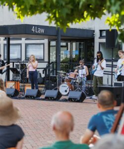 An audience watching a group of young musicians on an outdoor stage