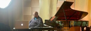A black man sitting in front of a grand piano