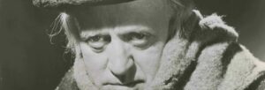 A black and white image of a grumpy man wearing a top hat