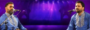 Two men sing into microphones with a purple lit stage behind them