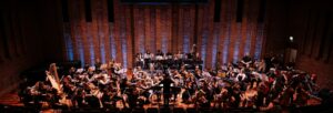 A large symphony orchestra made up of young people perform in Turner Sims.
