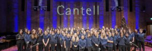 Primary school students stand on the Turner Sims stage facing the audience, with the words 'Cantell School' lit up on the wall behind.