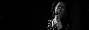 A black and white image of a young black woman singing into a microphone