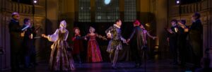 A group of 11 players wearing Renaissance dress on stage in the middle of a perfomance.
