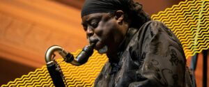 A man playing the saxophone with yellow abstract wiggly lines running behind him