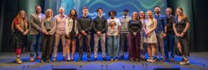 A group of people standing in front of a blue and green screen that reads 'student founder showcase'